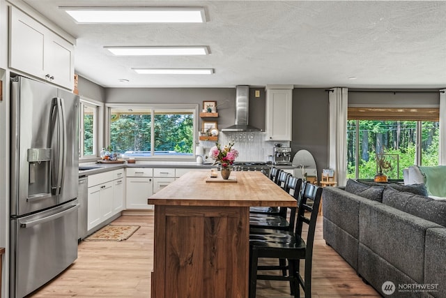 106 Barba Rd, Castle Rock, WA 98611 - kitchen featuring appliances with stainless steel finishes, wall chimney exhaust hood, open floor plan, a kitchen bar, and wood counters
