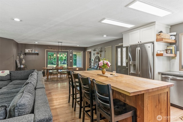 106 Barba Rd, Castle Rock, WA 98611 - kitchen featuring appliances with stainless steel finishes, butcher block countertops, white cabinetry, open floor plan, and a kitchen bar