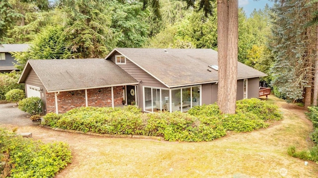 10761 Bill Point Crst NE, Bainbridge Island, WA 98110 - view of front of home featuring a garage, roof with shingles, a forest view, brick siding, and a front lawn