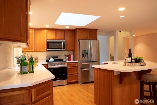 10761 Bill Point Crst NE, Bainbridge Island, WA 98110 - kitchen featuring stainless steel appliances, a skylight, brown cabinetry, recessed lighting, and light countertops
