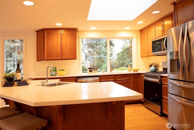 10761 Bill Point Crst NE, Bainbridge Island, WA 98110 - kitchen featuring appliances with stainless steel finishes, light countertops, a kitchen bar, recessed lighting, and light wood-style flooring