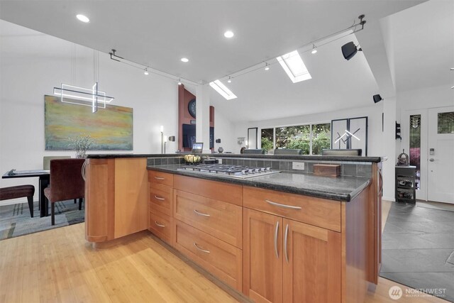 2212 186th Ave NE, Redmond, WA 98052 - kitchen with stainless steel gas cooktop, dark stone countertops, a skylight, vaulted ceiling, and track lighting