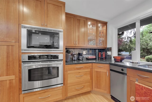 2212 186th Ave NE, Redmond, WA 98052 - kitchen with appliances with stainless steel finishes, tasteful backsplash, glass insert cabinets, dark stone counters, and light wood finished floors