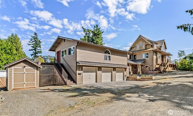 6117 39th Dr NW, Marysville, WA 98271 - view of front of property featuring stairway, driveway, a storage unit, an attached garage, and a standing seam roof
