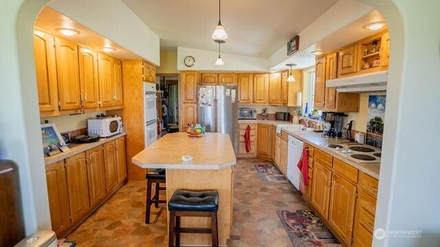 1448 Rd C NE, Moses Lake, WA 98837 - kitchen featuring under cabinet range hood, white appliances, light countertops, arched walkways, and a center island