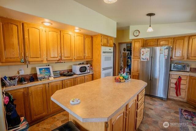 1448 Rd C NE, Moses Lake, WA 98837 - kitchen with white appliances, light countertops, a center island, brown cabinets, and decorative light fixtures