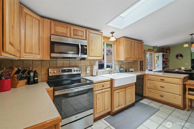 6338 Kirsop, Olympia, WA 98512 - kitchen featuring appliances with stainless steel finishes, a skylight, a peninsula, tasteful backsplash, and light countertops