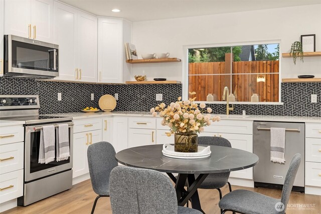 9224 36th Ave SW Unit 2, Seattle, WA 98126 - kitchen featuring stainless steel appliances, open shelves, light wood-style flooring, light countertops, and white cabinetry
