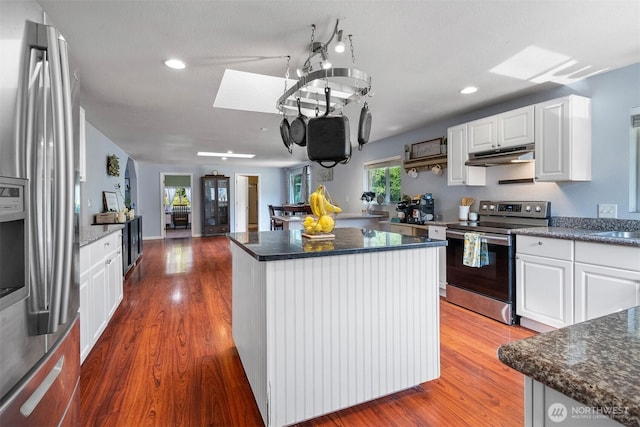6621 125th Street Ct E, Puyallup, WA 98373 - kitchen with appliances with stainless steel finishes, under cabinet range hood, a skylight, a center island, and wood finished floors