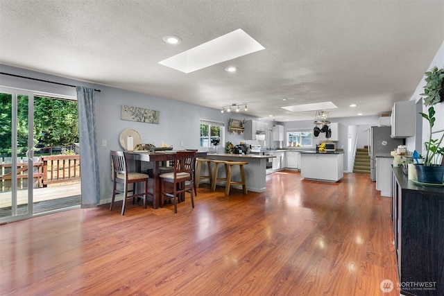 6621 125th Street Ct E, Puyallup, WA 98373 - dining room featuring a skylight, a textured ceiling, wood finished floors, stairway, and recessed lighting