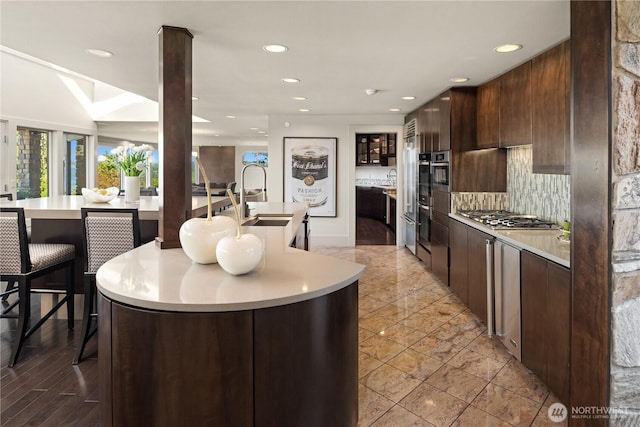 6411 View St NE, Tacoma, WA 98422 - kitchen with stainless steel gas stovetop, light countertops, recessed lighting, an island with sink, and dark brown cabinets