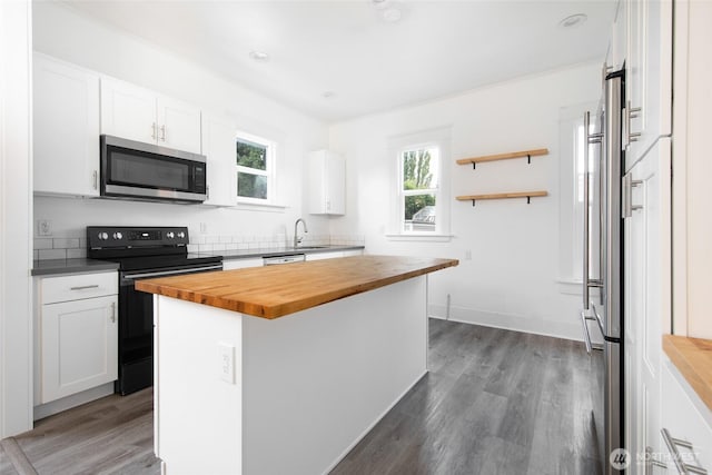 6753 14th Ave NW, Seattle, WA 98117 - kitchen with stainless steel microwave, butcher block countertops, electric range, white cabinets, and a kitchen island