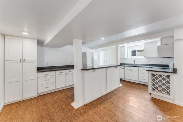 6753 14th Ave NW, Seattle, WA 98117 - kitchen featuring white appliances, light wood-style flooring, white cabinets, dark countertops, and recessed lighting