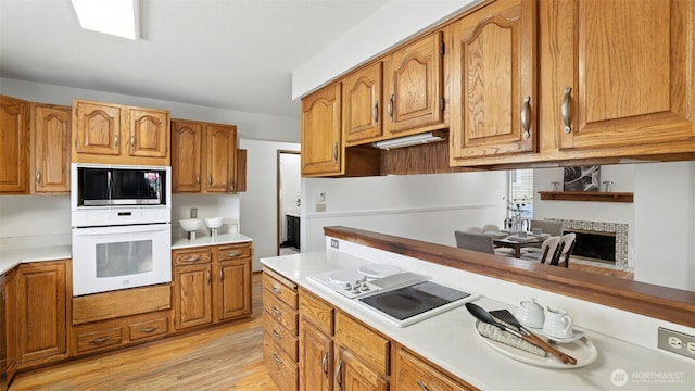 5109 S Myrtle St, Seattle, WA 98118 - kitchen with white oven, stovetop with downdraft, stainless steel microwave, light wood-style flooring, and brown cabinetry