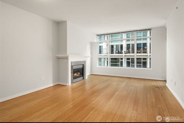 1420 Terry Ave Unit 907, Seattle, WA 98101 - unfurnished living room featuring hardwood / wood-style flooring and a glass covered fireplace
