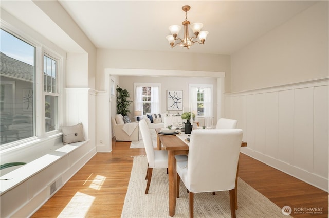 3207 N 9th St, Tacoma, WA 98406 - dining space featuring a decorative wall, light wood finished floors, wainscoting, and a chandelier