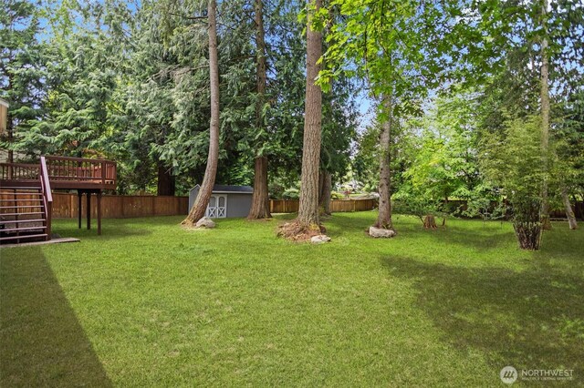 2021 224th Pl NE, Sammamish, WA 98074 - fenced backyard featuring stairway, a wooden deck, a storage shed, and view of wooded area