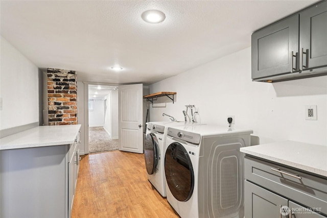611 Elizabeth St, Sumner, WA 98390 - laundry room with cabinet space, washing machine and dryer, light wood-style flooring, a textured ceiling, and recessed lighting