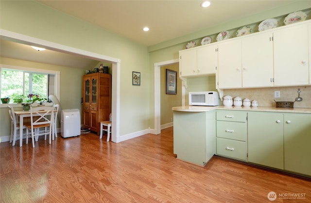 603 W 1st St, Nooksack, WA 98276 - kitchen featuring white microwave, light countertops, decorative backsplash, light wood-style flooring, and white cabinetry