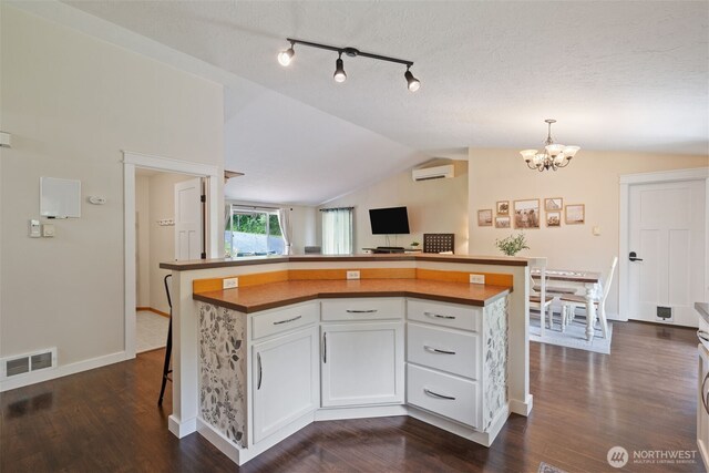 130 Kimberlund Ln, Chehalis, WA 98532 - kitchen with an AC wall unit, vaulted ceiling, white cabinets, a chandelier, and dark wood-style floors
