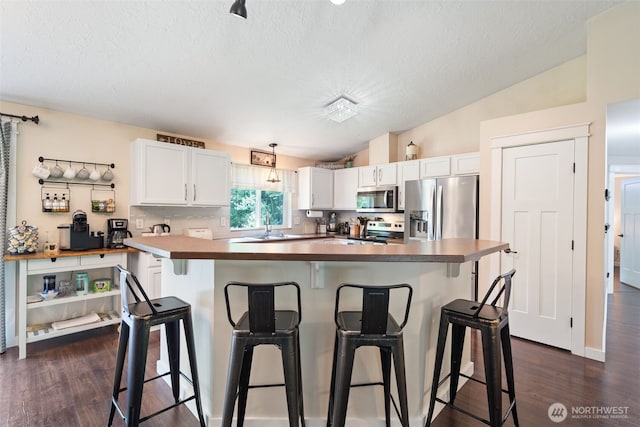 130 Kimberlund Ln, Chehalis, WA 98532 - kitchen with stainless steel appliances, white cabinets, a textured ceiling, dark wood-type flooring, and a breakfast bar area