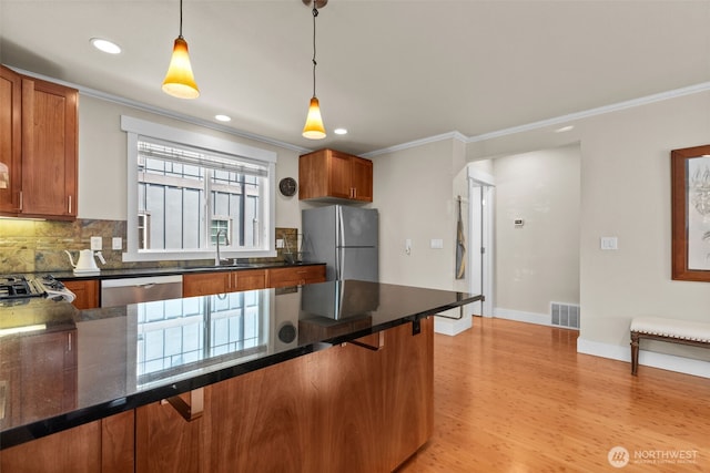 4252 Williams Ave W, Seattle, WA 98199 - kitchen featuring appliances with stainless steel finishes, crown molding, backsplash, light wood-style flooring, and hanging light fixtures