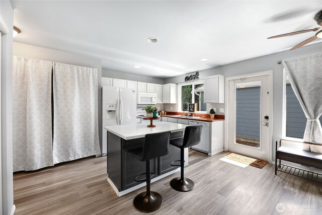 13421 Elk Ridge Rd SE, Monroe, WA 98272 - kitchen featuring white appliances, white cabinets, a ceiling fan, a breakfast bar, and light wood-type flooring
