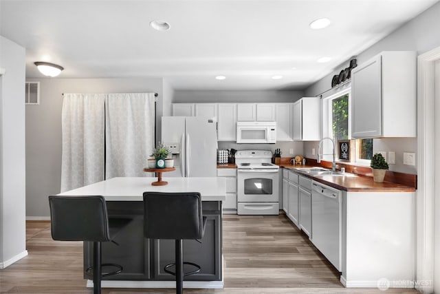 13421 Elk Ridge Rd SE, Monroe, WA 98272 - kitchen featuring white appliances, light wood-style flooring, a center island, recessed lighting, and a breakfast bar