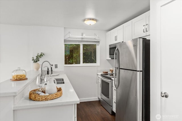 2636 22nd Ave W Unit 101, Seattle, WA 98199 - kitchen featuring appliances with stainless steel finishes, dark wood finished floors, light countertops, white cabinetry, and a peninsula