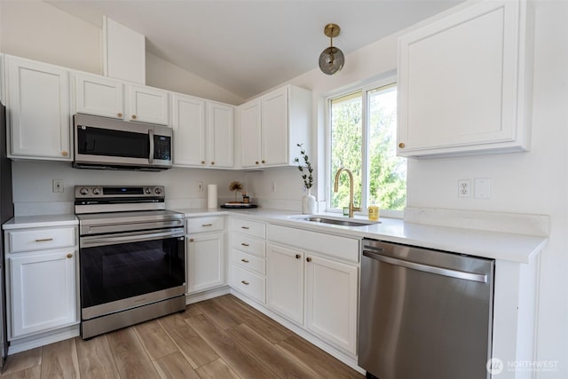 7801 144th Street Ct E, Puyallup, WA 98375 - kitchen with stainless steel appliances, lofted ceiling, white cabinetry, light countertops, and light wood finished floors