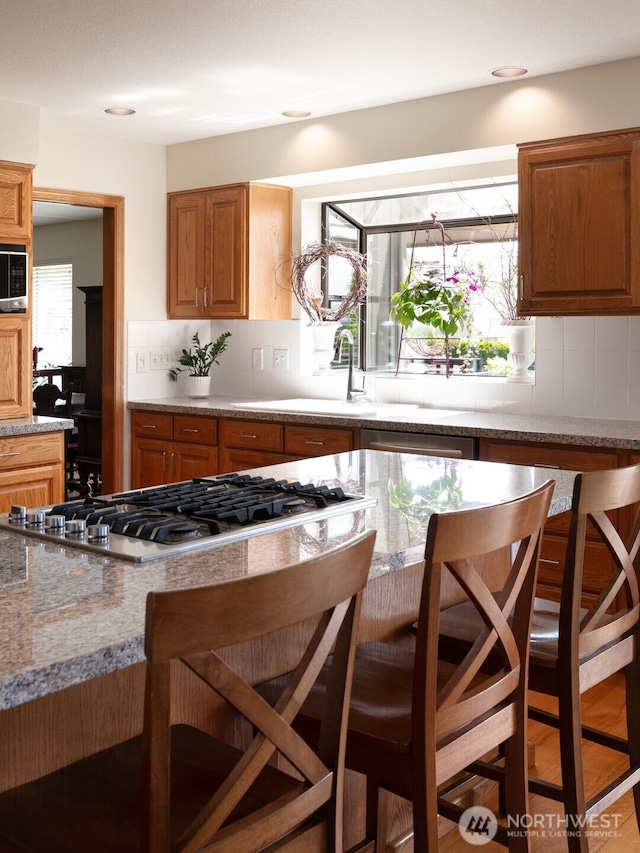 7610 Scenic Dr, Yakima, WA 98908 - kitchen featuring stainless steel appliances, a breakfast bar, decorative backsplash, and brown cabinets