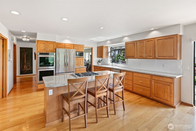 7610 Scenic Dr, Yakima, WA 98908 - kitchen featuring stainless steel appliances, recessed lighting, light wood finished floors, tasteful backsplash, and a kitchen breakfast bar