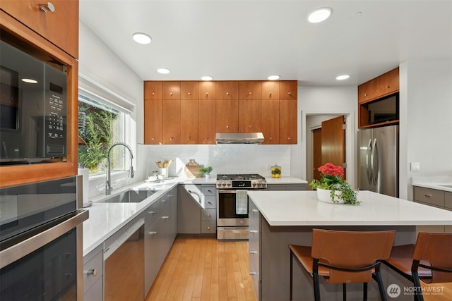 8812 NE 117th Pl, Kirkland, WA 98034 - kitchen featuring stainless steel appliances, under cabinet range hood, light wood finished floors, light countertops, and recessed lighting