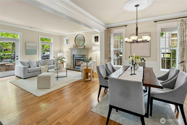 2621 NE Park Dr, Issaquah, WA 98029 - dining area featuring crown molding, plenty of natural light, a chandelier, light wood-type flooring, and a glass covered fireplace