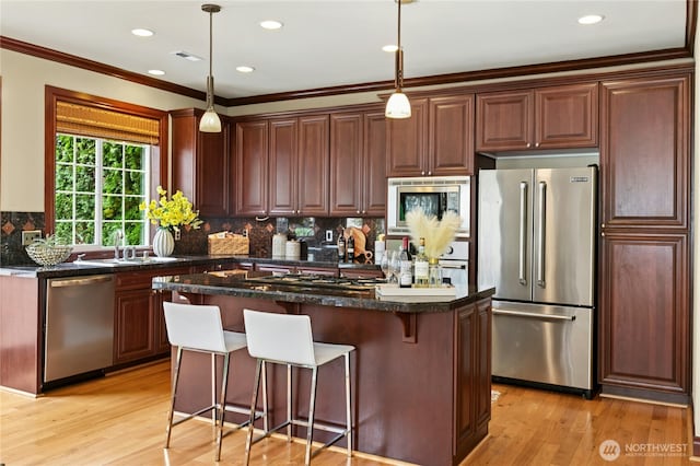 2621 NE Park Dr, Issaquah, WA 98029 - kitchen with stainless steel appliances, light wood-style flooring, tasteful backsplash, a kitchen bar, and recessed lighting