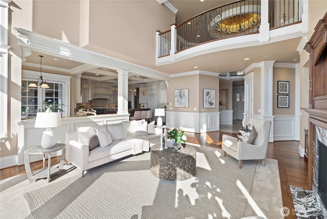 8071 W Mercer Way, Mercer Island, WA 98040 - living area featuring ornate columns, a high ceiling, wood finished floors, a fireplace, and ornamental molding