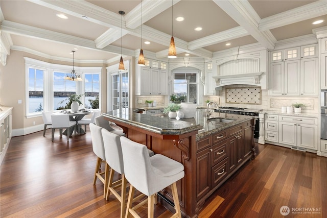 8071 W Mercer Way, Mercer Island, WA 98040 - kitchen with coffered ceiling, a kitchen bar, dark wood finished floors, dark stone counters, and healthy amount of natural light