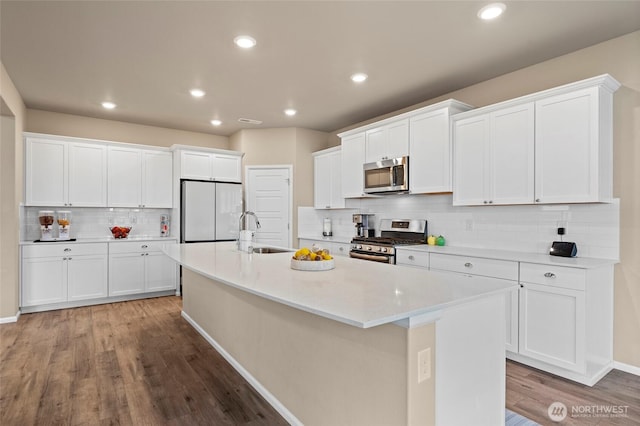 32803 Stuart Ave SE, Black Diamond, WA 98010 - kitchen featuring stainless steel appliances, decorative backsplash, an island with sink, light wood-type flooring, and white cabinetry