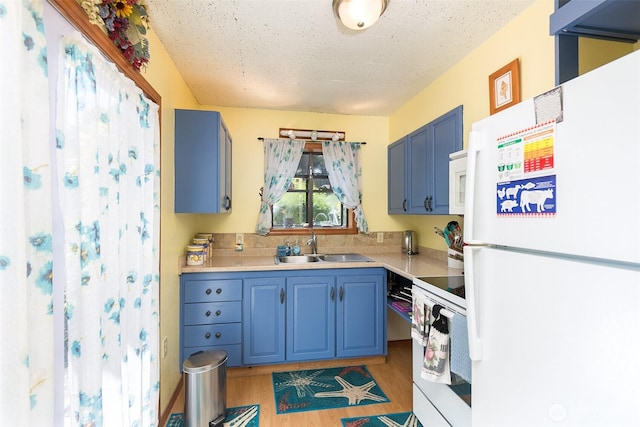 215 Amber Ln, Sequim, WA 98382 - kitchen with white appliances, blue cabinets, light countertops, light wood-style floors, and a textured ceiling