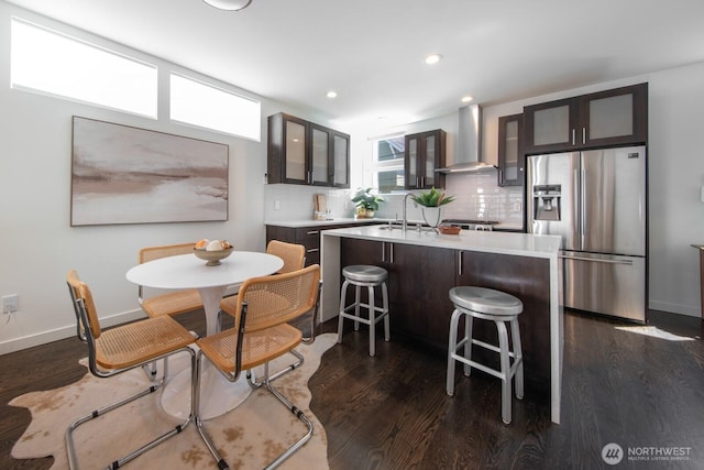 1136 10th Ave E Unit B, Seattle, WA 98102 - kitchen with stainless steel fridge, wall chimney exhaust hood, light countertops, a kitchen island with sink, and dark wood finished floors