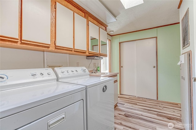 1700 Twin Peaks Dr Unit 71, Wenatchee, WA 98801 - laundry area featuring independent washer and dryer, light wood-type flooring, cabinet space, a skylight, and a textured ceiling