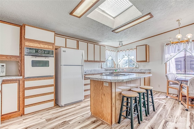 1700 Twin Peaks Dr Unit 71, Wenatchee, WA 98801 - kitchen featuring white appliances, a textured ceiling, a skylight, light wood-style flooring, and light countertops