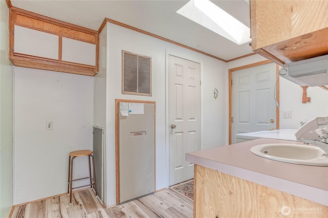 1700 Twin Peaks Dr Unit 71, Wenatchee, WA 98801 - kitchen with a skylight, light wood-style floors, light countertops, ornamental molding, and white cabinetry