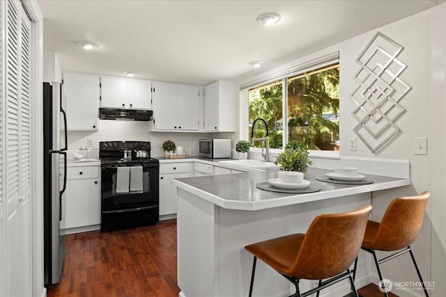 17019 426th Ave SE, North Bend, WA 98045 - kitchen featuring appliances with stainless steel finishes, under cabinet range hood, a peninsula, dark wood finished floors, and white cabinetry