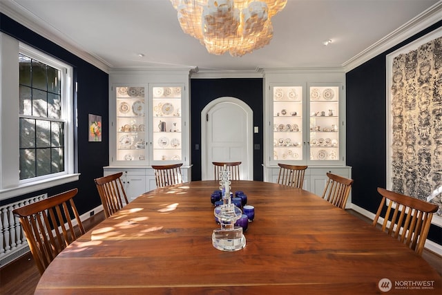 dining room with ornamental molding, a chandelier, and arched walkways
