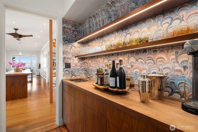 indoor wet bar featuring light wood-style floors and ceiling fan