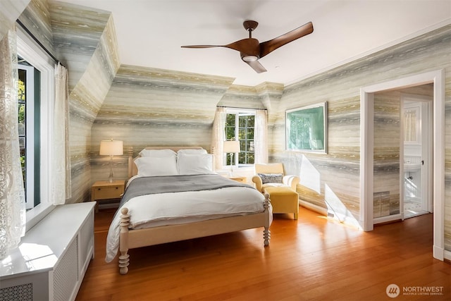 bedroom with wood finished floors, a ceiling fan, and wood walls