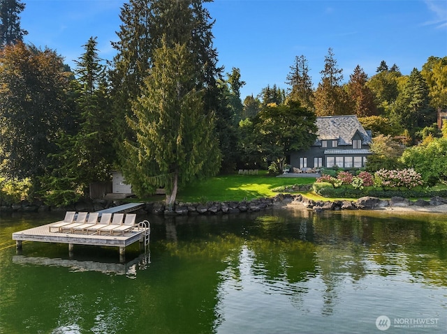 dock area with a water view, a lawn, and a forest view