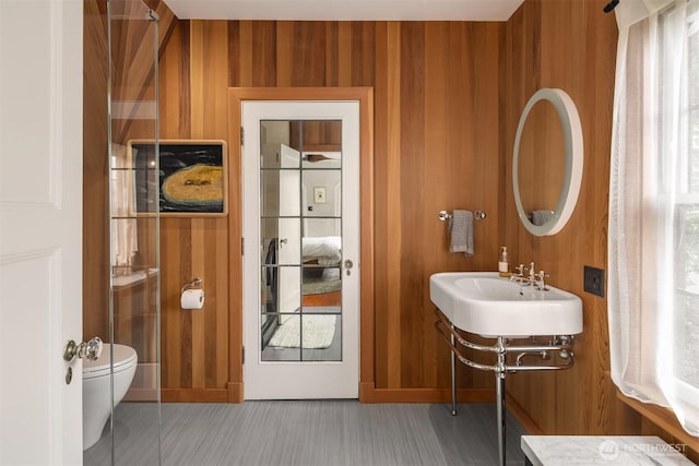 bathroom with toilet and wood walls