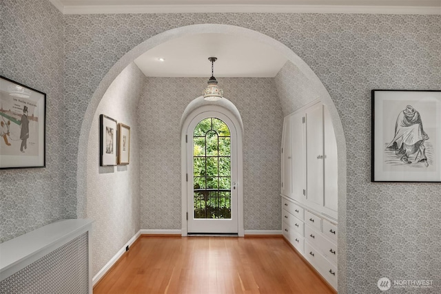 foyer featuring light wood-style flooring, radiator, and arched walkways